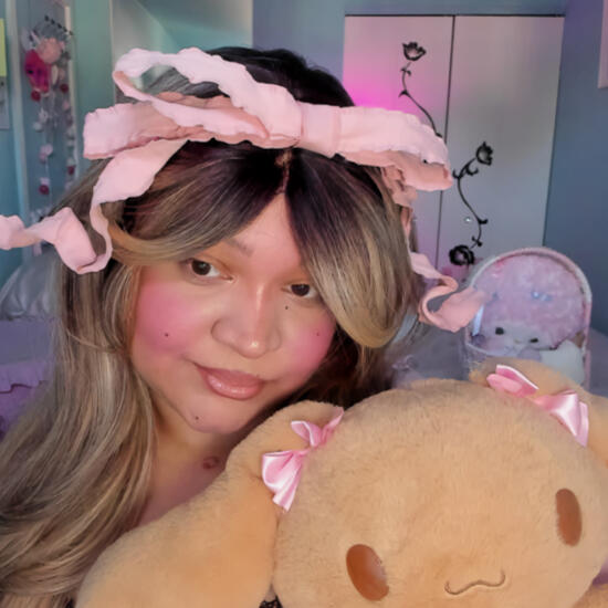 softestfairie holding a lovelymocha stuffed animal, and wearing a very large pink curly bow headband.